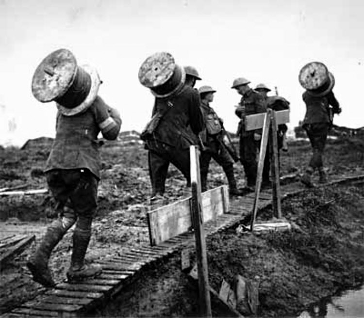 Sappers from the Royal Engineers carrying drums of signalling cable in 1917